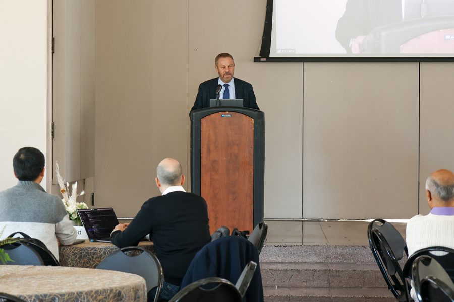 Dean Ed Schlesinger stands at the podium onstage and welcomes the audience