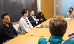 A group of individuals sit around a table attending the breakout session focused on general discussion of security-related abstracts.