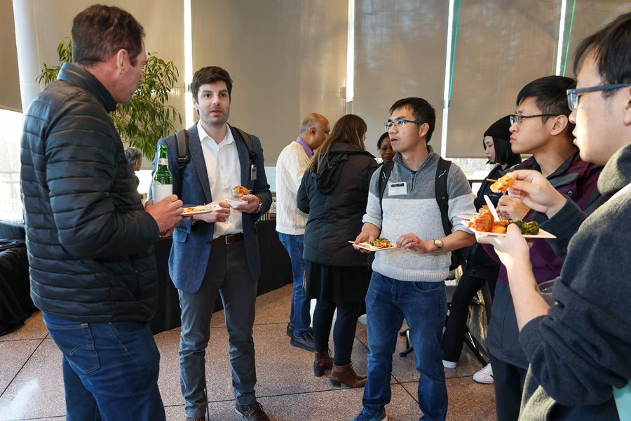 Event attendees stand in a circle and converse while enjoying refreshments.